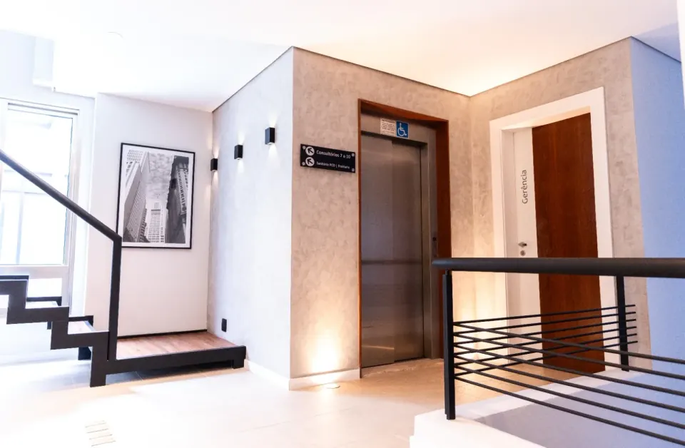 Hall interno com elevador acessível e sinalização para sanitário PCD
